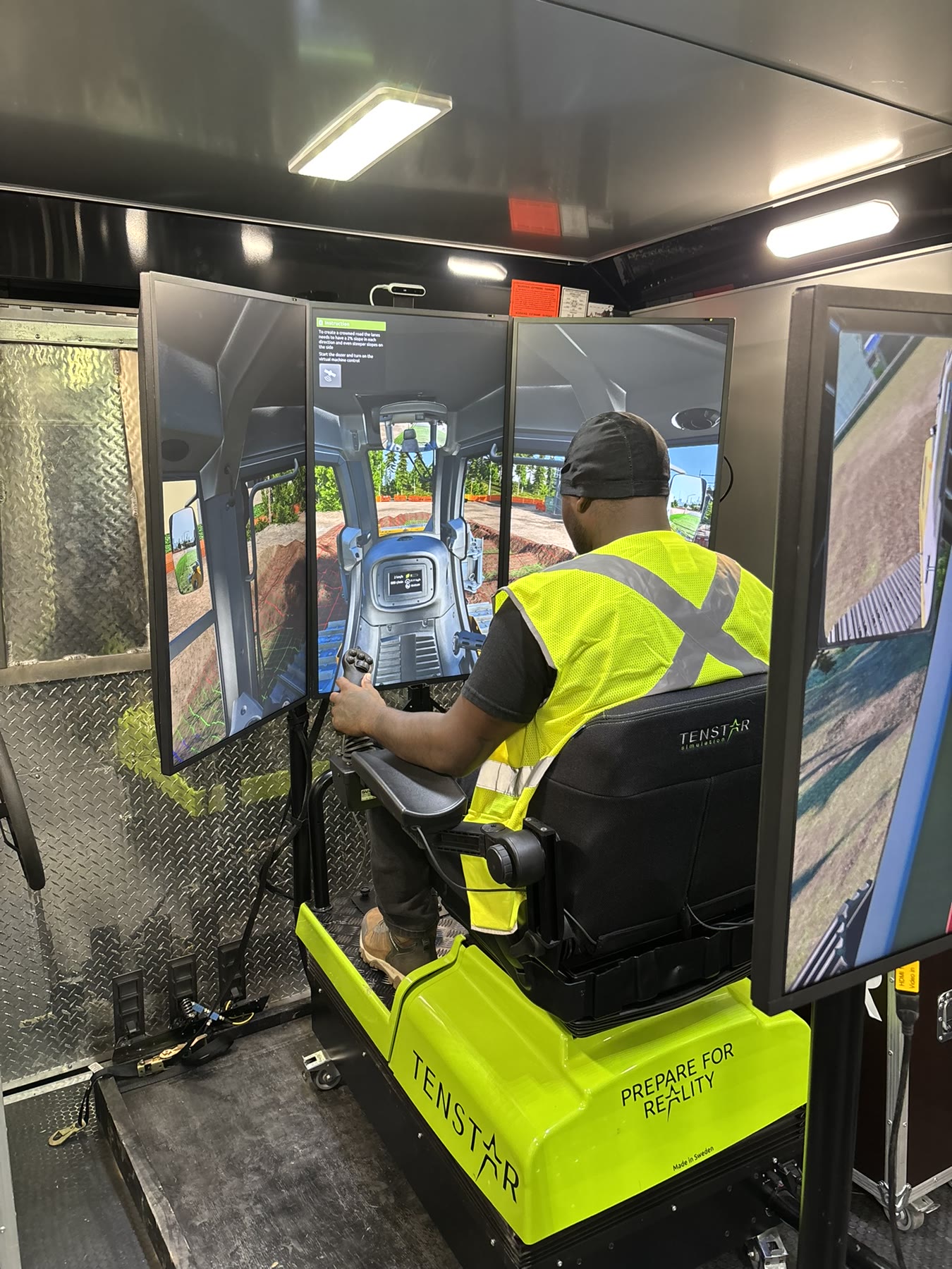 Operator practicing dozer controls on a multi-screen simulator