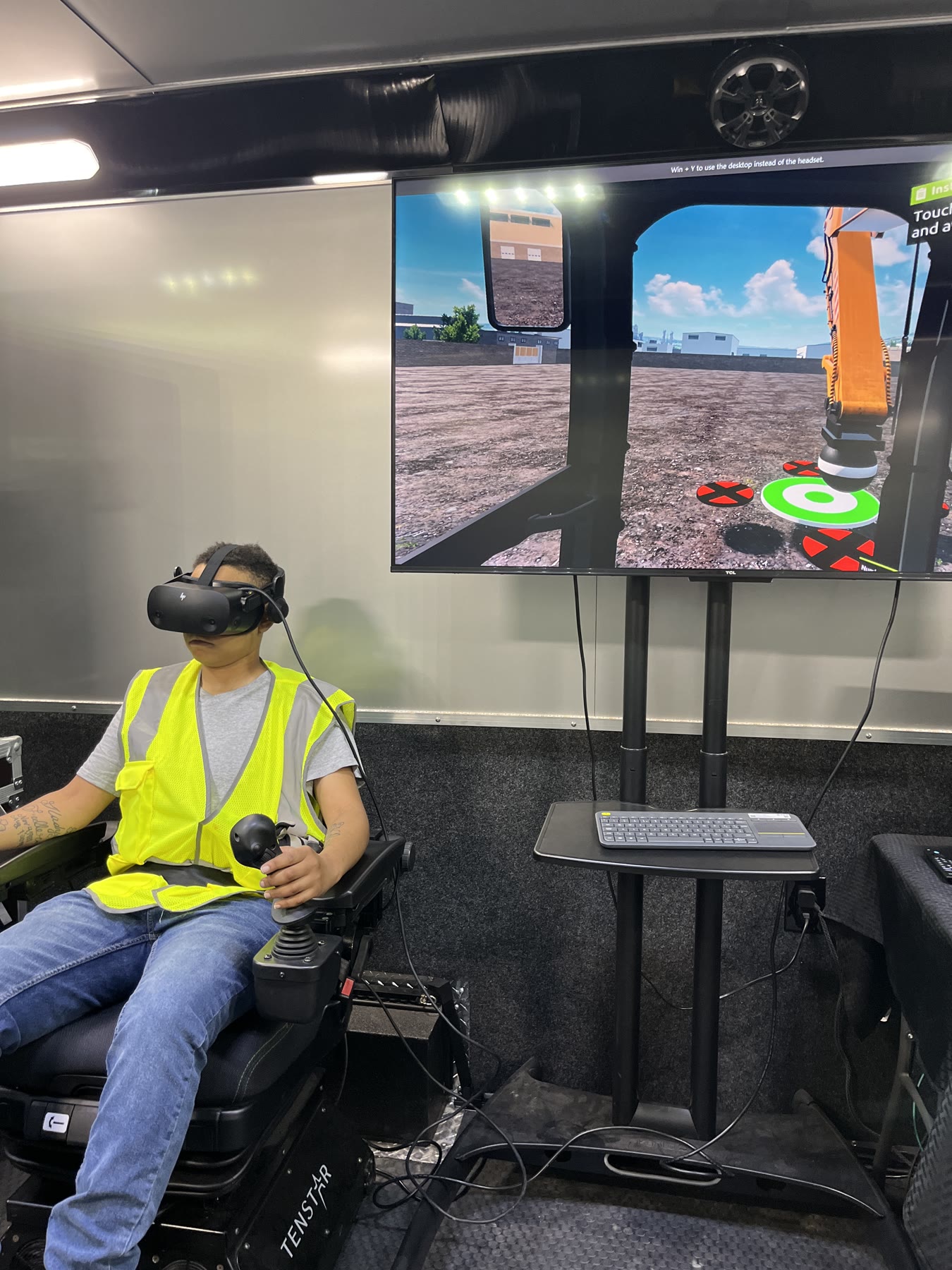 Operator using a virtual reality headset and joystick during excavator simulator training